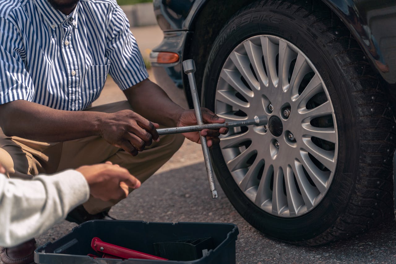 heros-img An adult demonstrating how to change a tire to a teenager, focusing on teamwork and learning.